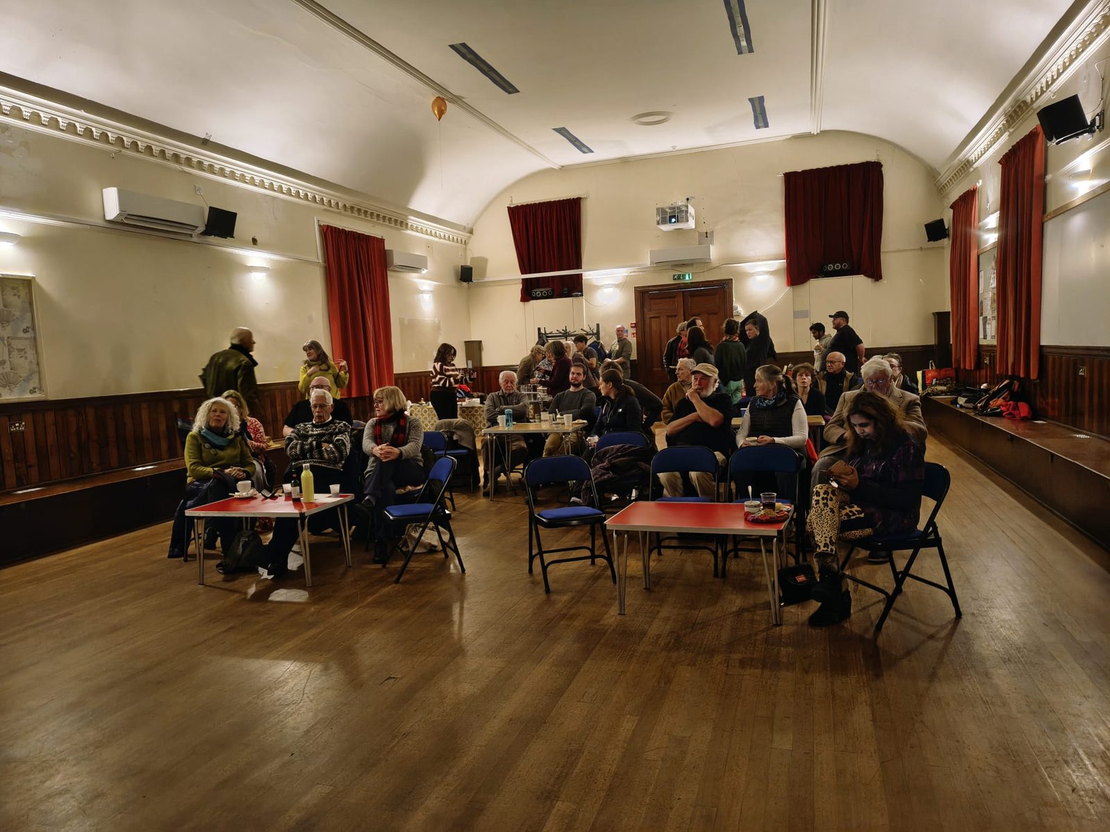 People chatting over tea in the hall before a screening